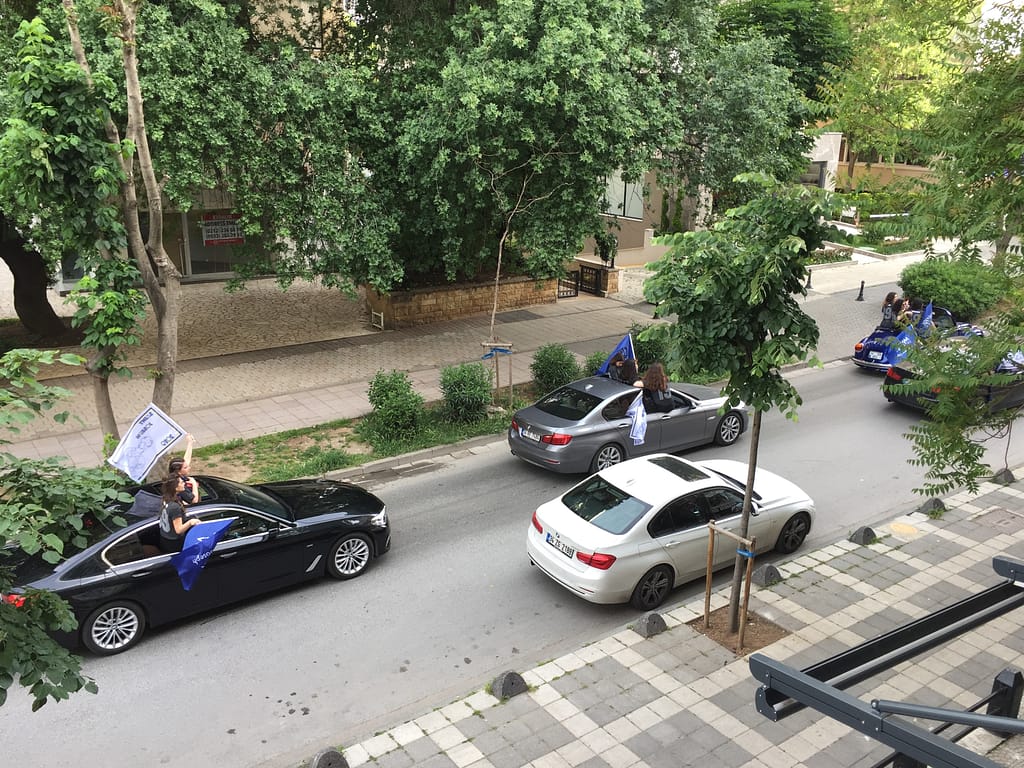 Liikennettä Istanbulissa Fenerbahçessa Aasian puolella. Nuoret heiluttavat lippuja autoista.